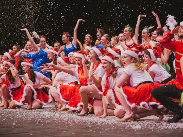 Cheerful dance troupe in Santa hats celebrating.